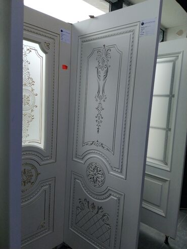 taxta qapilarin renglenmesi: Ağ rəngli qapı, üzərində klassik naxışlar və dekorativ elementlər var
