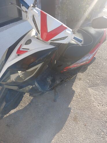 Ağ və qara rənglərdə olan moped skuter, qırmızı detallarla vurğulanıb