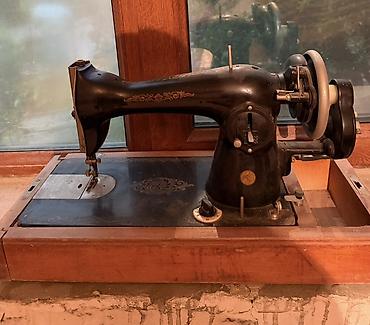 qədim tikiş maşınları: Tünd rəngli metaldan hazırlanmış köhnə mexaniki tikiş maşını. Maşın — 2