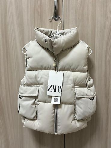 теплый жилет: Стеганая жилетка Zara бежевого цвета, предназначенная для детей — 1