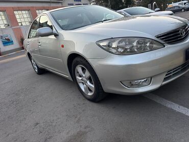 дополнительная фара: Серебристый седан Toyota Camry с четырьмя дверями и легкосплавными