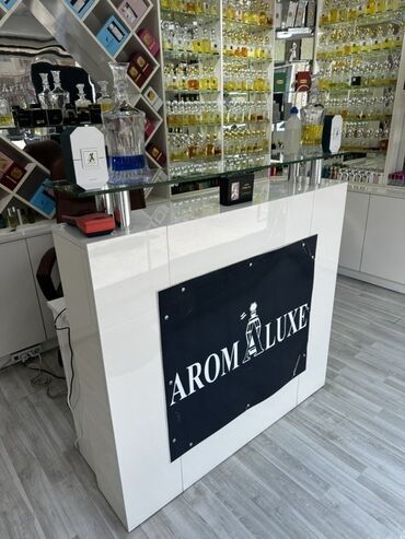 Sifarişlə işçi masaları: Ağ rəngli, parlaq səthli qəbul masası. Ön tərəfində "AROM LUXE" yazısı