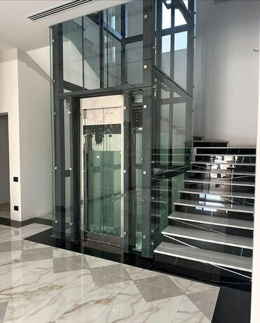 metlax pilleken: Şəffaf şüşə panelləri və qara metal konstruksiyalı müasir lift