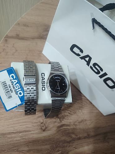casio saatlari: CASIO brendinin gümüşü rəngli metal kəmərli və qara siferblatlı kişi — 3