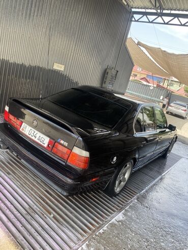 сполер е34: Чёрный седан BMW M5 в кузове E34. Этот автомобиль сочетает в себе