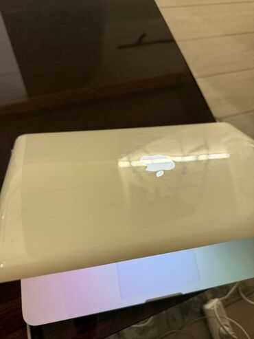 Masaüstü kompüterlər və iş stansiyaları: Apple MacBook – ağ korpuslu, işıqlanan Apple loqosu ilə. Texniki
