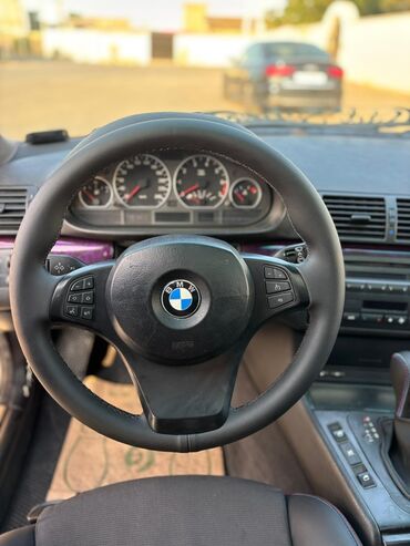 Tavalar: Daxili tənzimləmə düymələri olan qara rəngli BMW sükanı. Sükanın