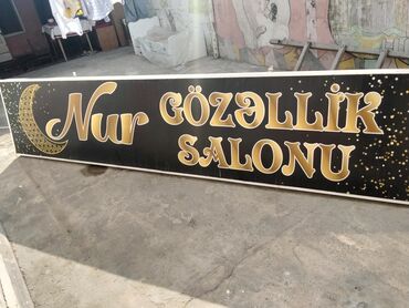 Reklam lövhələri: Qara fonda qızılı rəngdə "Nur Gözəllik Salonu" yazısı olan reklam