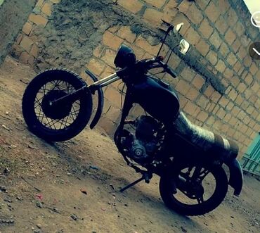 Motonəqliyyatın icarəsi: Ön təkərində böyük ön fənər və qara qanad olan qara motosiklet. Geniş