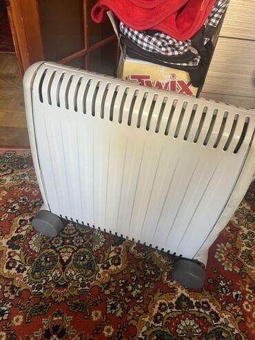qizdirici radiatorlar: Ağ rəngdə, təkərləri olan radiator. Otağı isitmək üçün əlverişlidir