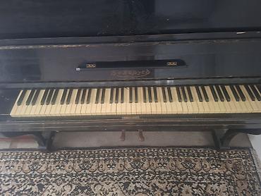 piano az: Qara rəngli, klassik üslubda akustik pianino. Korpus üzərində — 1