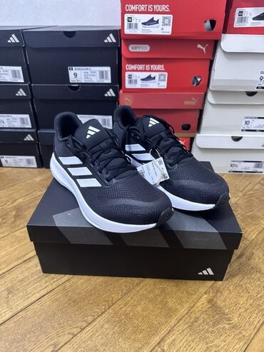 Krasofkalar və idman ayaqqabıları: Qara rəngli, üç ağ zolaqlı Adidas idman ayaqqabıları. Yüngül və rahat