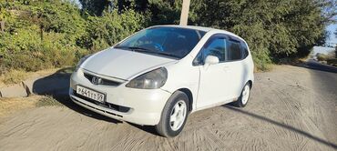шины разноширокие: Белый пятидверный хэтчбек Honda Fit. Автомобиль оснащен тонировкой