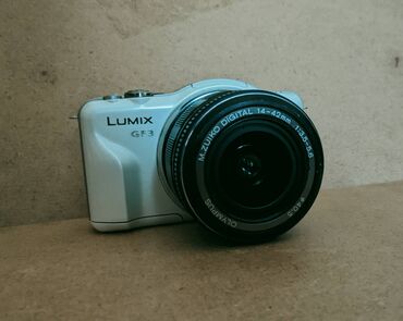 camera dslr: Panasonic LUMIX GF3 белого цвета. Оснащена объективом Olympus M.ZUIKO