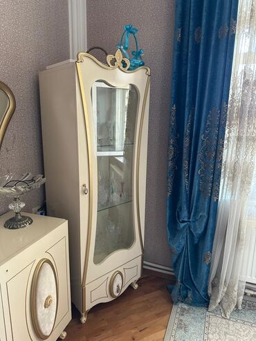 Masalar və oturacaqlar: Şüşəli qapısı olan, əyri formalı, ağ rəngli vitrin şkafı. Şkafın