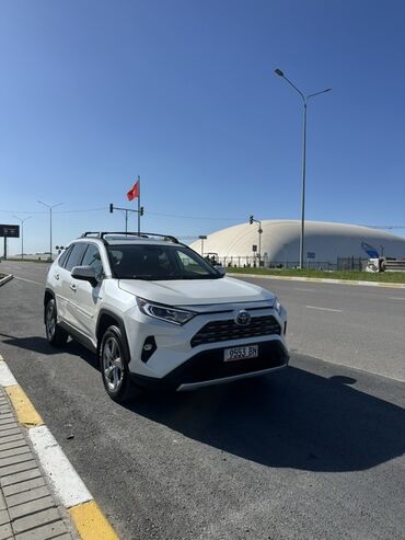 тайота раф 4: Белый кроссовер Toyota RAV4 с рейлингами на крыше. Автомобиль оснащен