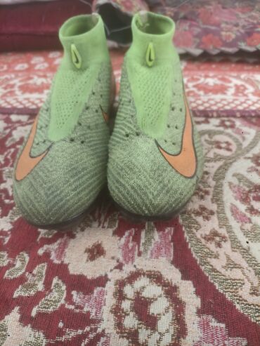 Кроссовки и спортивная обувь: Пара футбольных бутс Nike, преимущественно зеленого цвета с оранжевым