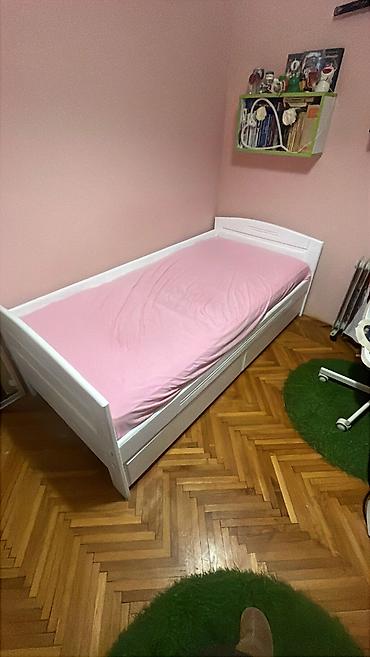 Singl krevet od punog drveta ofarban u belu boju. Krevet ima dve