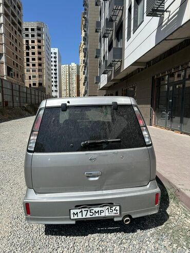 домик на колесо: Серебристый минивэн Nissan Cube первого поколения, идеально подходящий