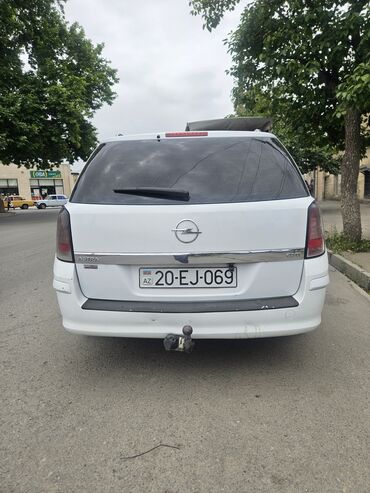 opel vectra: Ağ rəngdə olan Opel Astra universal avtomobili. Avtomobilin arxasında