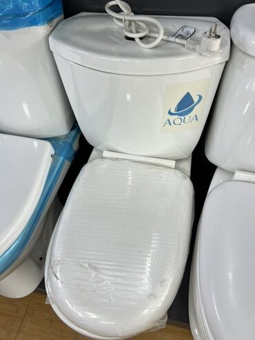 туалеты уличные: Унитаз-компакт белого цвета с логотипом Aqua на бачке. Модель оснащена