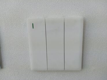 ev qaplsl: Divarda quraşdırılmış, üç düyməli, ağ rəngli elektrik açarı. Yaşıl
