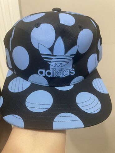 Baş geyimləri: Qara rəngdə, mavi nöqtələri olan Adidas kepkası. Kepkanın ön