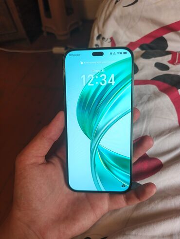 ucuz telefon qiymetleri: Yaşıl rəngdə müasir smartfon. Cihazın ekranında "dinamik ada"