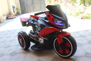Uşaq üçün elektrik maşınları: Qırmızı və qara rənglərdə olan uşaq elektrik motosikleti. İki yan qutu