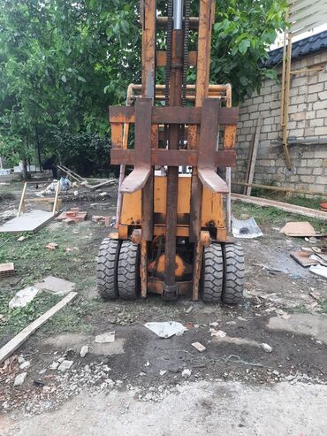 İşlək vəziyyətdə olan sarı rəngli forklift. Anbarlarda və tikinti