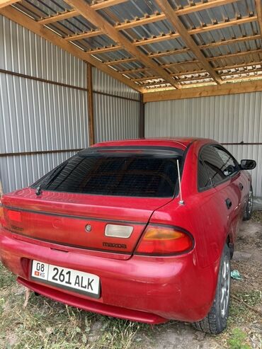 спортивная машина: Автомобиль Mazda 323 красного цвета. Модель оснащена четырехдверным