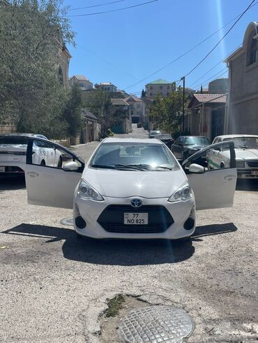 a 3 2015: Ağ rəngdə Toyota Aqua hetçbek avtomobili. Kompakt ölçüsü sayəsində