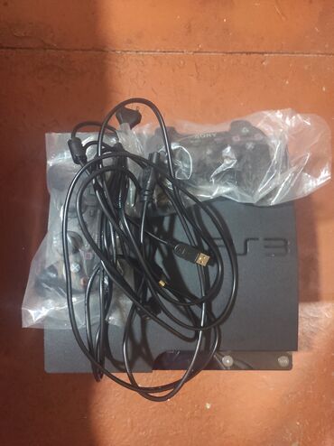 Sony PlayStation 3 oyun konsolu qara rəngdədir və iki nəzarətçi