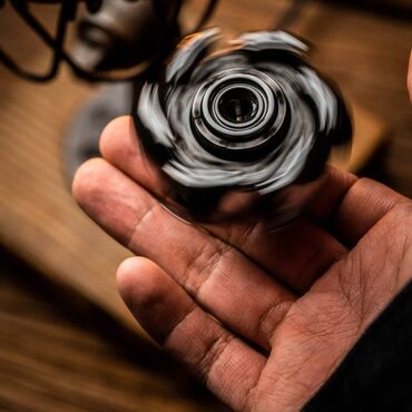 антистрессовые игрушки fidget cube: Fırlanan qara rəngli fidget spineri, əldə tutmaq üçün rahat dizayna