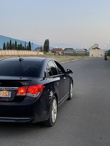 xacmazda ucuz avtomabiller: Qara rəngdə olan Chevrolet Cruze avtomobili. Arxa tərəfdən görünür