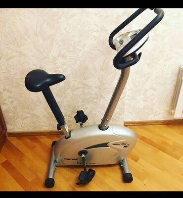 Digər trenajorlar: Gümüşü rəngdə Proteus velosiped trenajoru. Qara oturacağı və qolları