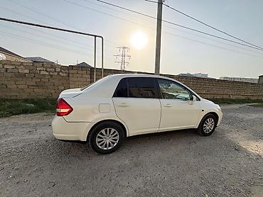 nisan note: Ağ rəngli Nissan Tiida sedan. Avtomobilin salonu açıq bej tonlarda — 3