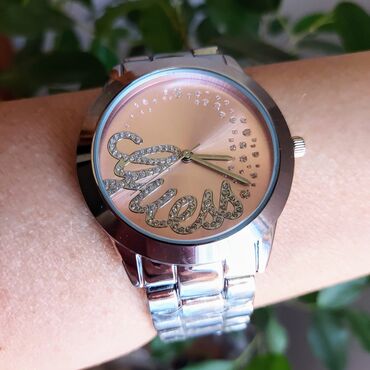 zenski cardigan elegantniji sa etiketom pise: Divan Guess sat u srebrnoj boji, sa roze kućištem. Brojčanik je