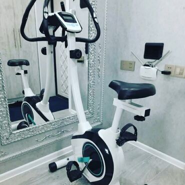 Elliptik trenajorlar: Ağ və qara rənglərdə olan stasionar velosiped trenajoru. Üzərində