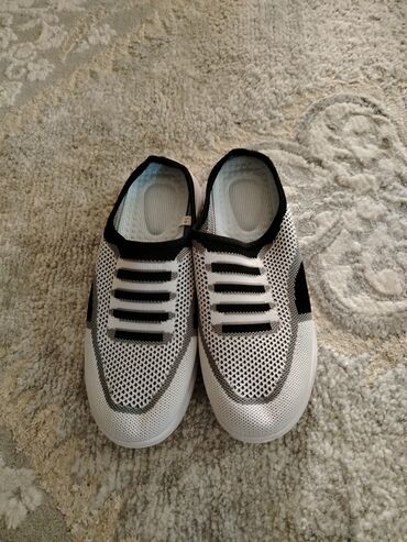 Krasofkalar və idman ayaqqabıları: Ağ və qara rənglərdə, açıq dizaynlı slip-on idman ayaqqabıları. Hava