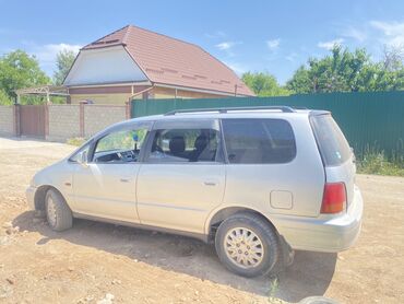 семиместные машины: Серебристый минивэн Honda Odyssey, подходящий для семейных поездок и