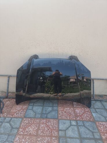 Qara rəngli avtomobil kapotu. Üst səthində yüngül cızıqlar və aşınma