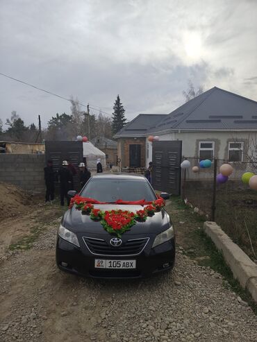 машине сатылат: Черный седан Toyota Camry, украшенный красными и зелеными цветочными