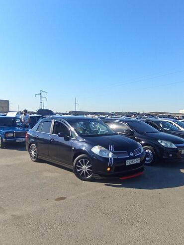 akkumulyator satisi: Tünd göy rəngdə, dördqapılı Nissan Tiida sedan avtomobili. Avtomobil