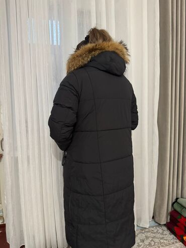 женские куртки российского производства: Длинный женский пуховик черного цвета с капюшоном и натуральным мехом