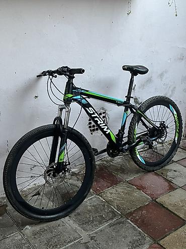 boyuk velosiped: Qara rəngli, yaşıl və mavi vurğulara malik dağ velosipedi. Velosipeddə — 2