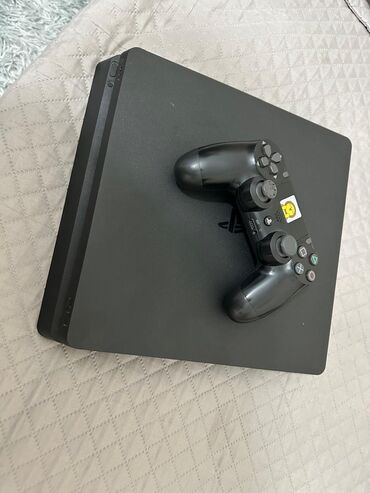ps4 dualshock: Qara rəngli, nazik dizaynlı PlayStation 4 oyun konsolu. Üzərində