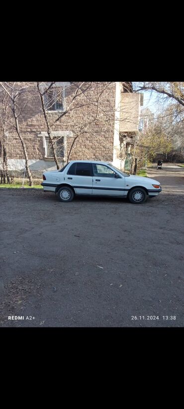 Mitsubishi: Автомобиль Mitsubishi Lancer в кузове седан белого цвета. Это