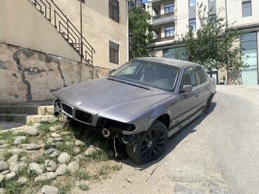 BMW: Gümüşü rəngdə olan BMW 7 seriyalı avtomobil. Ön hissəsində zədələr var