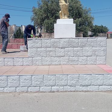 sumqayıt kafel metlax zavodu: Ağ daş bloklardan tikilmiş, qızılı rəngli heykəlin yerləşdiyi hündür